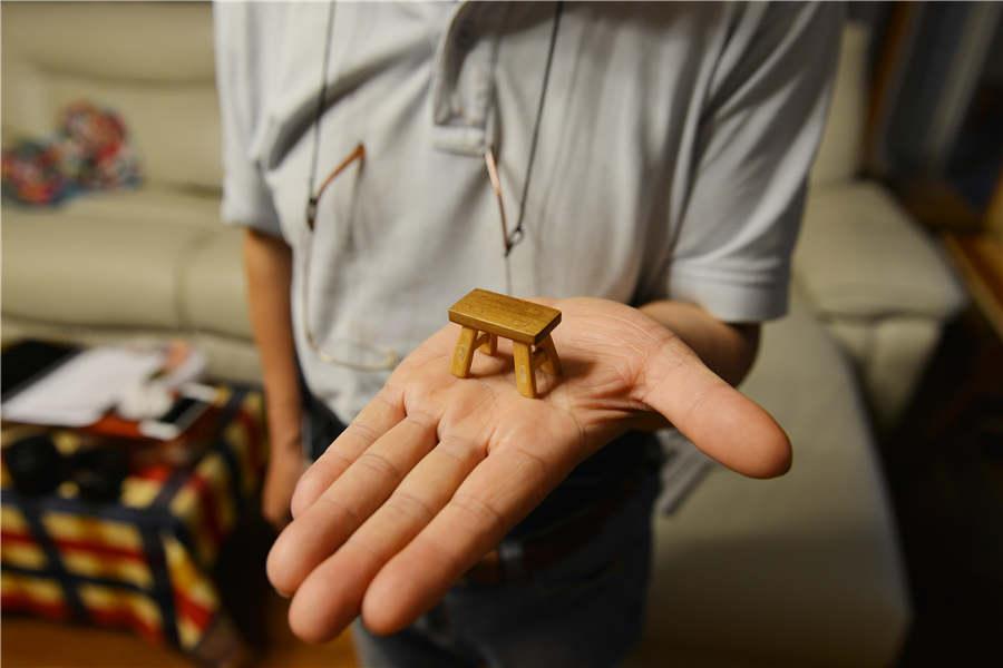 Chen Hesheng shows a miniature wooden bench.  (Photo/Asianewsphoto)